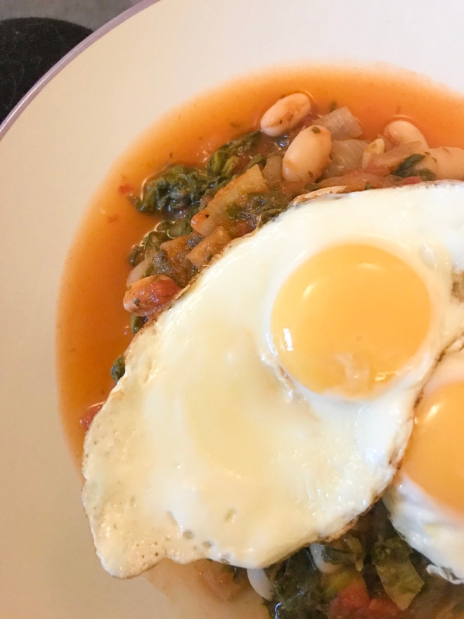 Tomatoes, cannellini beans and spinach topped with fried eggs